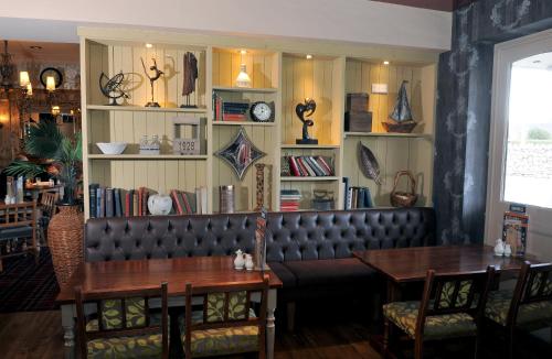 圣亚萨Talardy, St Asaph by Marston’s Inns的餐厅设有皮革长凳、桌子和书架