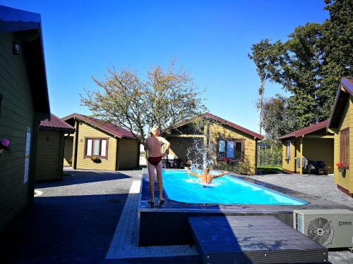 帕兰加鲍尔莱度假屋的站在游泳池旁平台上的男人