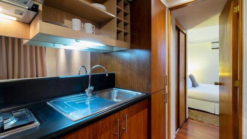 圣地亚哥Stay Essential Apartments by Time Hotel & Apartments的带水槽的厨房和1间带床的房间