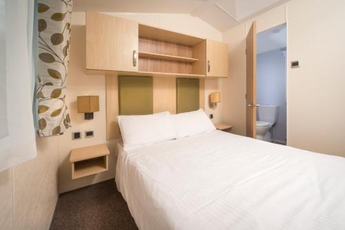 库姆马丁Sandaway Holiday Park的卧室配有白色的床和卫生间