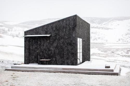 米湖Aska, Modern Cabin的一座黑色的建筑,位于一座雪覆盖的山顶上