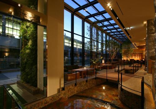 高崎可可大酒店的大堂设有大型玻璃天花板和桌子。