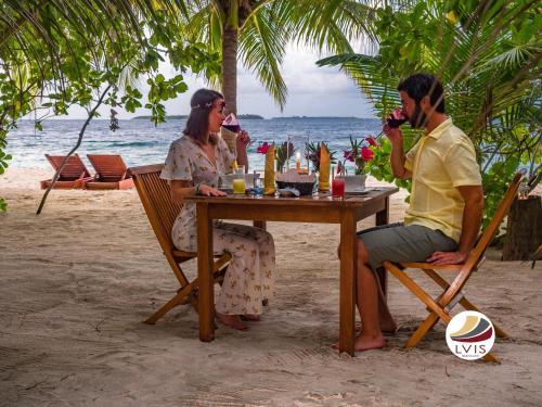 达拉万度乐维斯布朗库拉酒店的坐在海滩桌子上的男人和女人