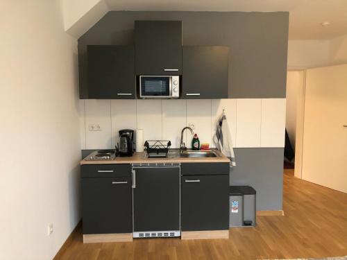 不莱梅Newtown Apartments Bremen的一间小厨房,配有黑色橱柜和水槽