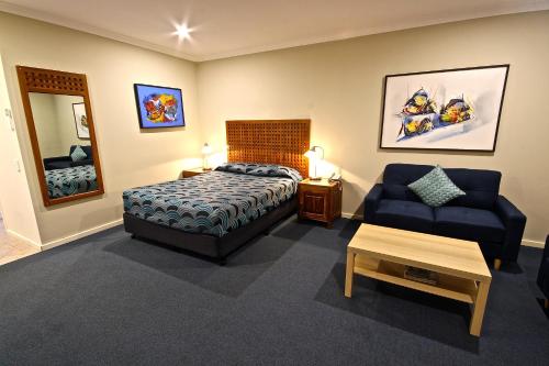 班伯里Bunbury Motel and Apartments的一间卧室配有一张床、一张沙发和一把椅子
