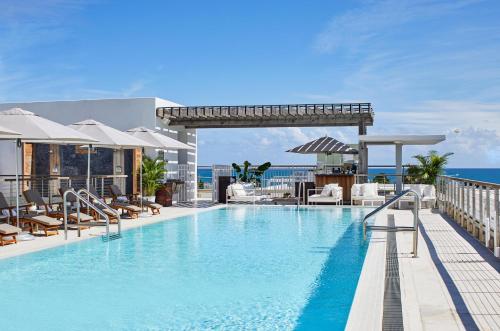 迈阿密海滩南海滩贝特西酒店的一座位于一座建筑顶部的游泳池,其背景是大海