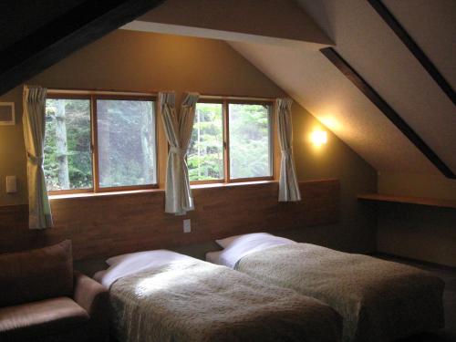 轻井泽轻井泽町山林小屋的带2扇窗户的客房内的2张床