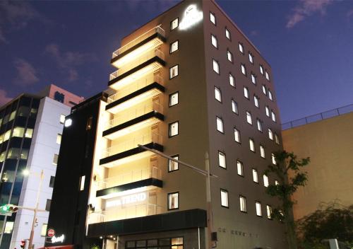 沼津Hotel Trend Numazu Ekimae的一座高大的建筑在晚上点燃