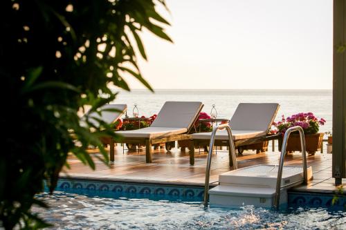 阿吉奥斯伊欧尼斯Kenta Beach Hotel的海滩上带桌椅的甲板