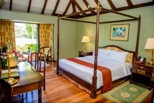 内罗毕温莎高尔夫酒店及乡村俱乐部的一间卧室配有四柱床和一张桌子