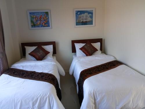 范县Supunnika Garden Guesthouse的配有白色床单的客房内的两张床