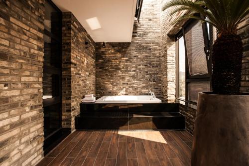 首尔SR Hotel Sadang的带浴缸和砖墙的浴室
