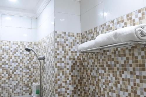 玛琅Morse Guest house的浴室铺有棕色和白色瓷砖,设有淋浴。