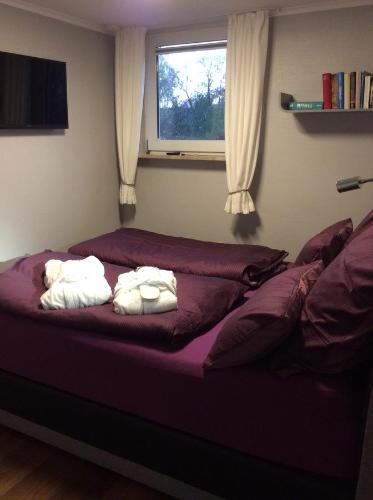 柏林Ferienwohnung Mahlsdorf-Ein Quäntchen mehr的一间卧室设有两张带紫色床单的床和窗户。