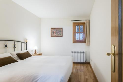 卡尼略Apartamento Refugi的白色的卧室设有白色的床和窗户。
