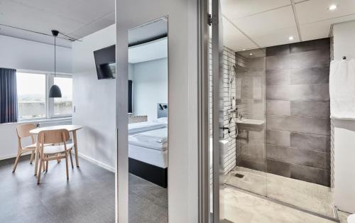 奥胡斯Zleep Hotel Aarhus Viby的带淋浴的浴室以及带椅子的桌子