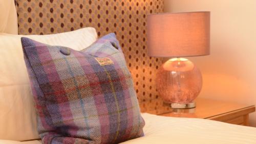 威廉堡Torlinnhe Guest House的一张带枕头的床和一张桌子上的台灯