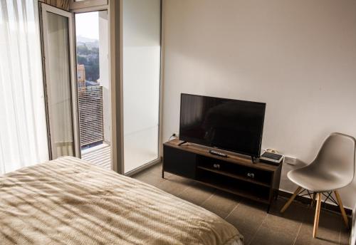 瓦尔帕莱索Loftbellavistavalparaiso的一间卧室配有一张床、一台电视和一把椅子