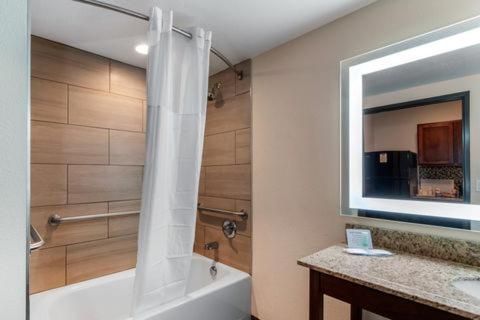丹佛MainStay Suites Denver International Airport的浴室配有浴缸、淋浴和镜子