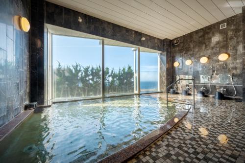 鹤冈市庄内阳光度假酒店的设有带大型游泳池及大窗户的浴室