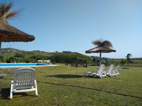 坦迪尔Cabañas Calihue的游泳池旁的四把白色椅子和一把遮阳伞