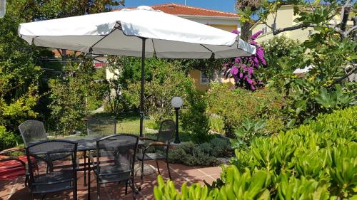 拉布Apartments Antica的花园的遮阳伞下的桌椅