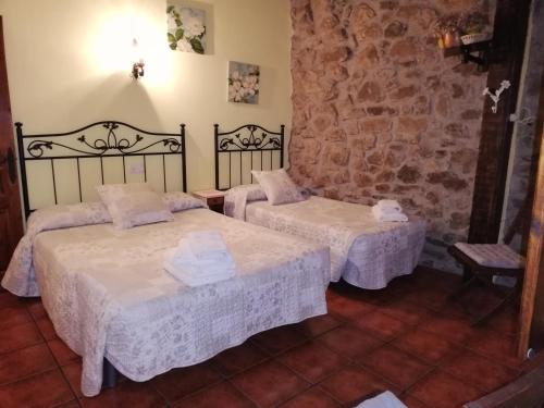 奥耶多LA CASUCA Y LA CABAÑA的一间设有两张床和石墙的房间