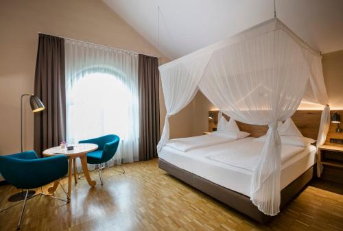 巴特布卢毛布鲁茂百水温泉大饭店的一间卧室配有天蓬床和桌椅