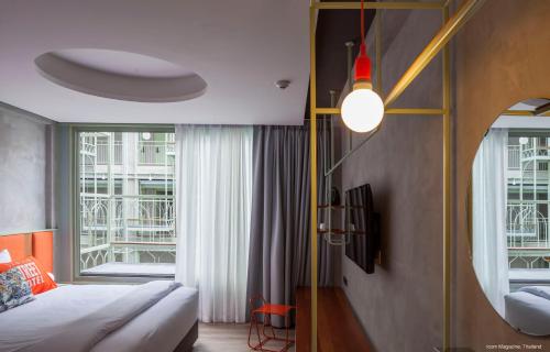 曼谷Samsen Street Hotel的一间卧室设有一张床和一个大窗户