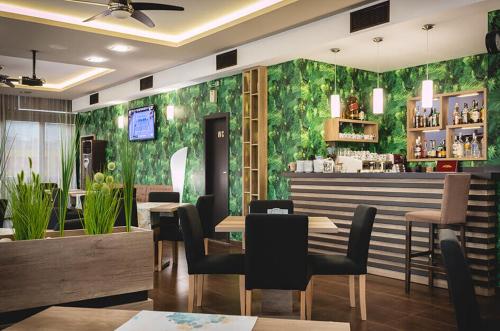 季米特洛夫格勒Семеен Хотел Естило的餐厅设有绿色墙壁,配有桌椅
