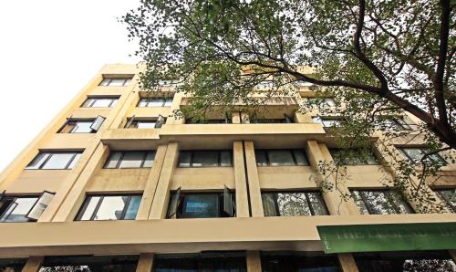 孟买The Legend Hotel- Santacruz Near Mumbai International Airport的一座带窗户和一棵树的高大的棕褐色建筑