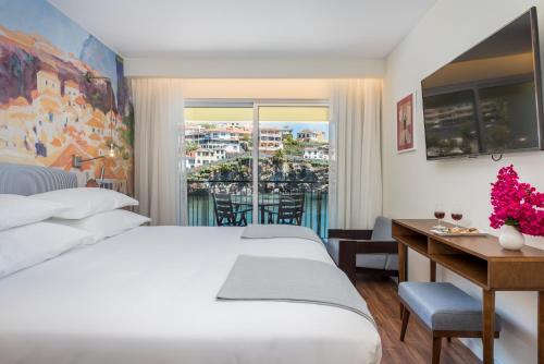 卡马拉-德洛布什Pestana Churchill Bay的酒店客房设有两张床、一张书桌和一个窗户。