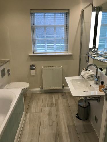 Glasbury格拉斯伯里夫伊尔斯酒店的一间带两个盥洗盆、浴缸和卫生间的浴室