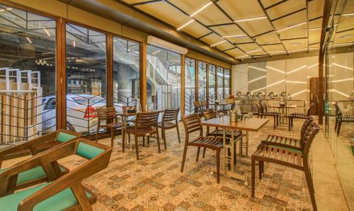 孟买Hotel Metropole Inn的餐厅设有木桌、椅子和窗户。