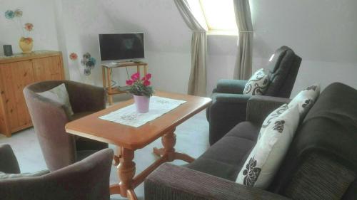 魏玛Ferienwohnung Marion Franke的客厅配有椅子和一张带花瓶的桌子