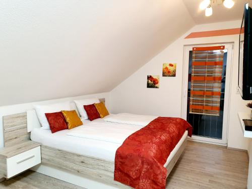 鲁斯特Kempf Apartments的一间卧室配有白色的床和红色和黄色枕头