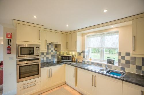 Aldringham2 Hazelwood的厨房配有白色橱柜、水槽和窗户。