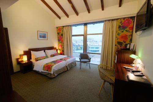 拉马拉皇庭酒店的一间卧室配有一张床、一张书桌和一个窗户。