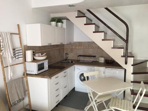 圣巴托洛梅ETNICAN的一间厨房,配有白色橱柜和一个带桌子的楼梯