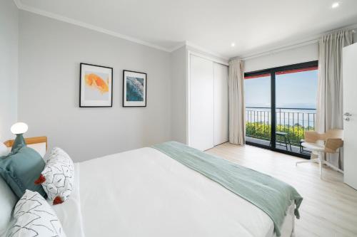 蓬塔杜帕戈Vilas Felicidade Rocha by An Island Apart的白色卧室设有一张大床和一个阳台
