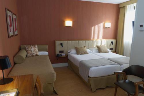 马德里Hospedium Hotel Los Condes的酒店客房,设有两张床和一张沙发