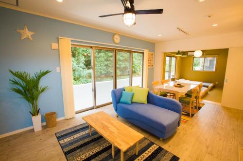 恩纳#3LDK一軒家 #長期滞在可能 #海まで4分-- Starry Sky Resort Okinawa --的客厅配有蓝色的沙发和桌子
