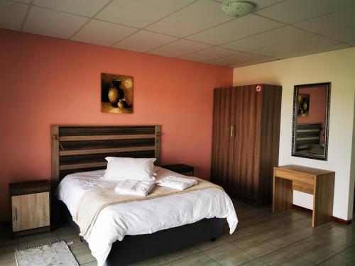 GhanziPlot 19的一间卧室配有一张带橙色墙壁的大床