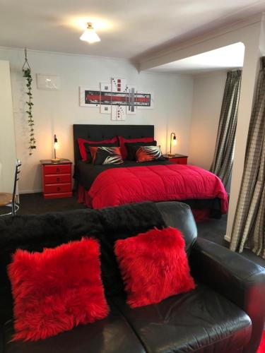阿卡罗阿Hideaway - A Couples Retreat的一间卧室配有一张带红色枕头的床和一张沙发