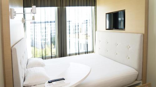 华沙声音花园机场酒店的卧室配有白色的床、电视和窗户。
