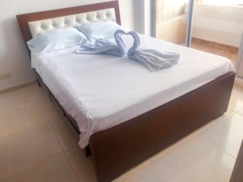 吉拉尔多特Sensacional Apartamento Reserva Peñon Girardot的一张带白色床单和毛巾的床
