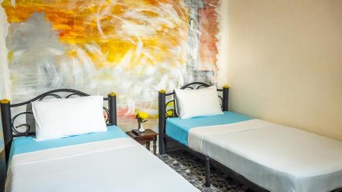 卡马拉海滩萨比那客栈的墙上画画的房间里设有两张床