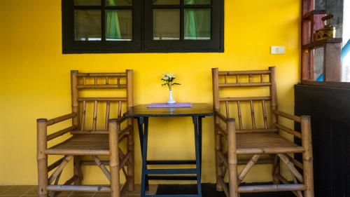 卡马拉海滩萨比那客栈的黄色墙壁的房间里设有两把椅子和一张桌子