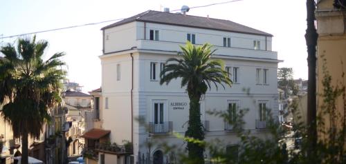 拉默齐亚泰尔默Albergo Centrale的一座白色的建筑,前面有棕榈树