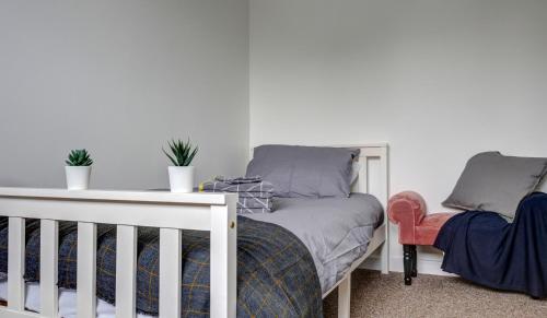 迪德科特Didcot- Private Flat with Garden & Parking 04的一间卧室,上面有一张婴儿床和两株植物